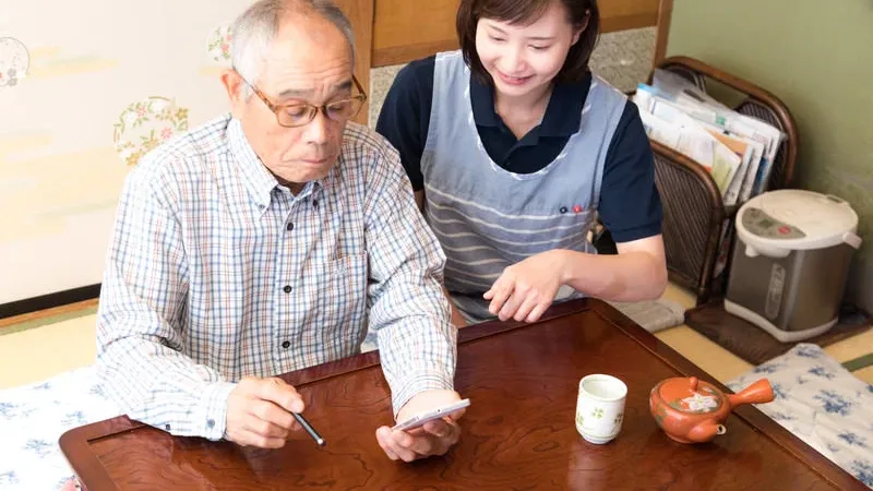 高齢者と介護士が一緒にスマートフォンで映像を確認する様子